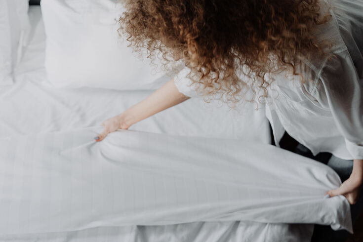 A woman feeling her sheets for its comfort level