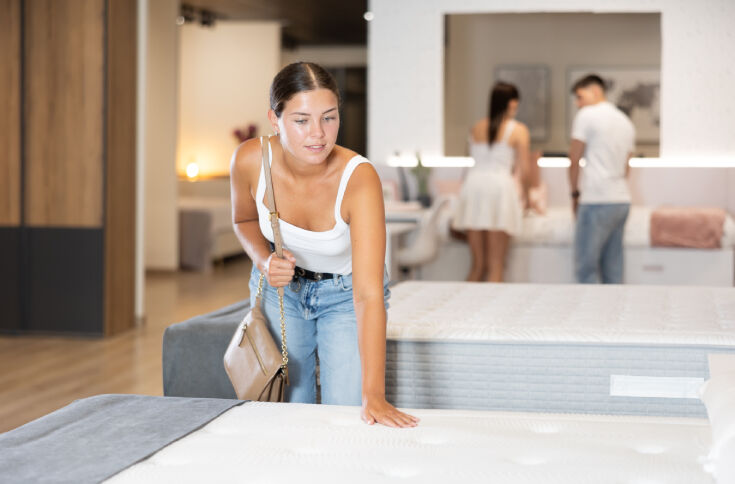 Woman pressing on a mattress to test its feel in a showroom