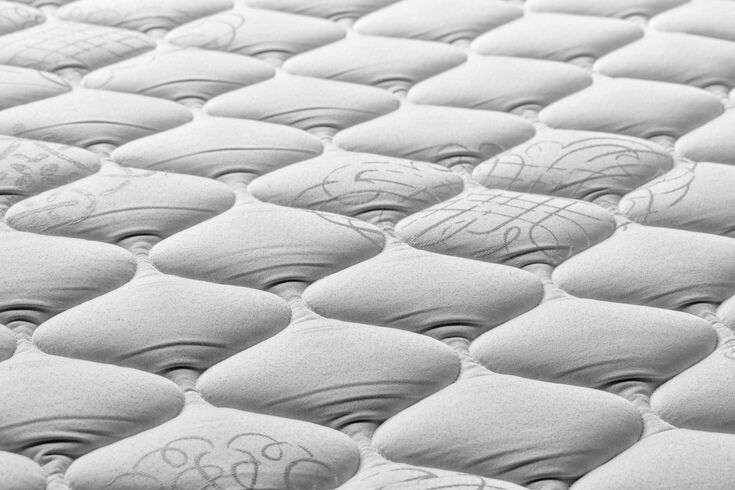 Close-up of the quilted top panel of a mattress showing its padded surface