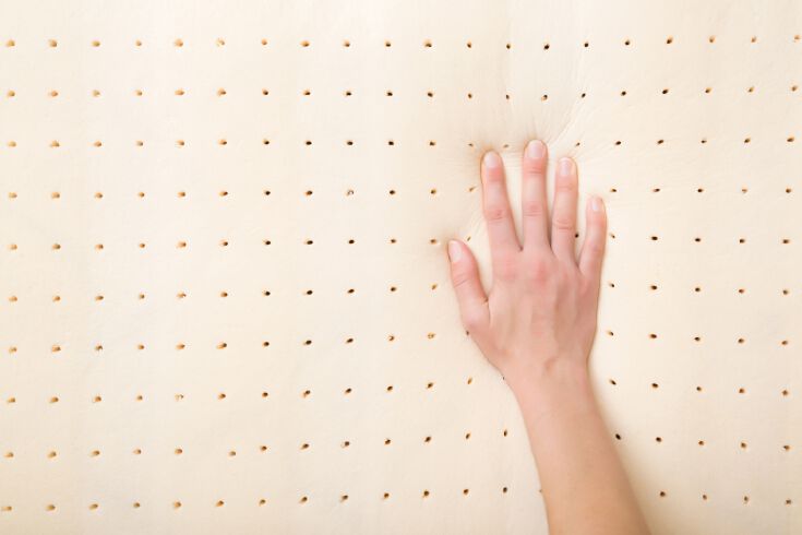 Hand pressing into a pinhole-patterned latex mattress layer