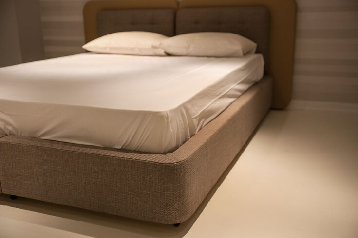 Mattress on an upholstered base with a fitted sheet, shown from the side