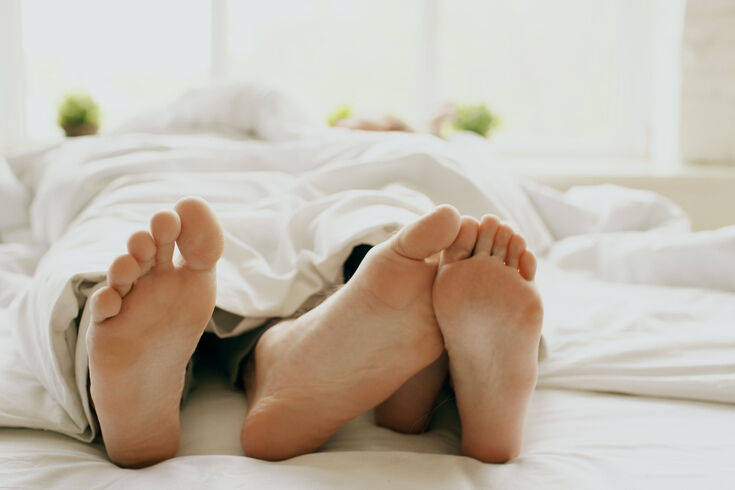 Bare feet poking out from under a duvet at the end of a bed