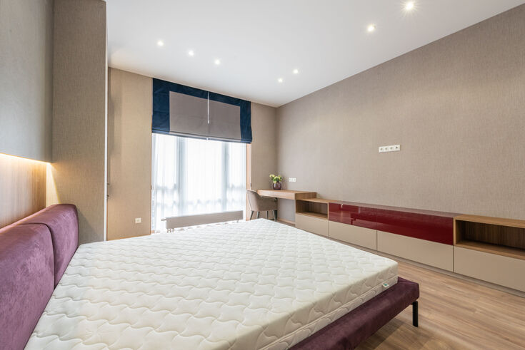New quilted mattress sitting bare on a bed frame in an empty bedroom