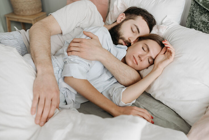 A full-size bed centered in a small guest room with one nightstand