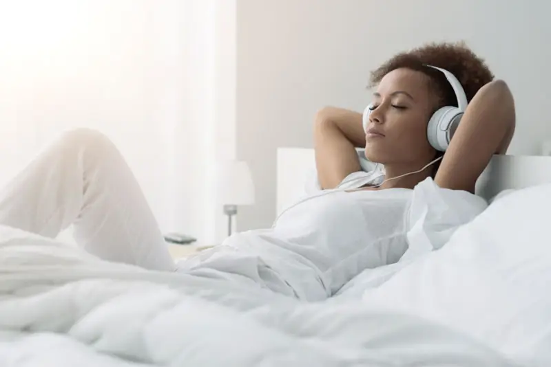 Relaxed while listening to music in the bedroom with headphones on.